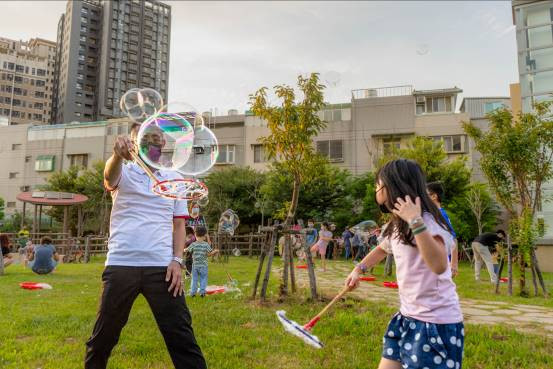 林冠年參與中崙社區集會，與小朋友一起在公園吹泡泡。