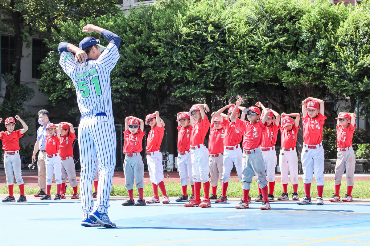 臺北興富發棒球隊球員吳界煌帶領小球員們做熱身操。