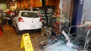 白色自小客車失控撞進全聯超市，造成玻璃門碎裂，部分架上貨物散落一地／讀者提供