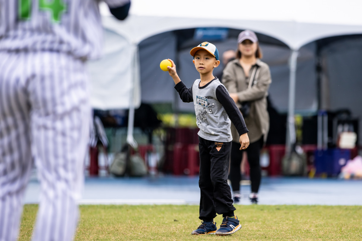 臺北興富發棒球隊球員耐心指導小朋友進行傳接球訓練。