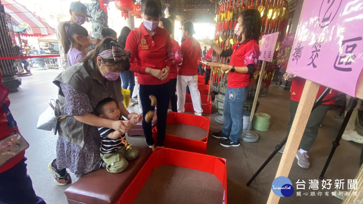 潭水亭觀音媽廟舉辦擲筊大賽，年僅3歲男童在家長指導下體驗。