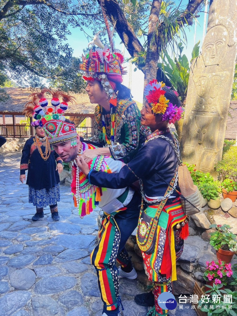 著裝參觀排灣族的貴族婚禮，並嘗試用原住民結婚揹新娘的姿勢揹起女性同伴。（九族文化村企劃部提供）