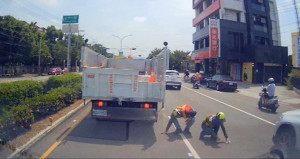 清潔隊員在車陣中撿拾民眾掉落之千元大鈔