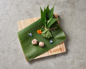 前菜部分，則取材於獵人以「八角金盤葉」包裹小米與煙燻肉作為狩獵口糧的故事，轉化為文化再現的「獵徑充糧—林霧蒸香獵人粽」。（林業及自然保育署南投分署提供）