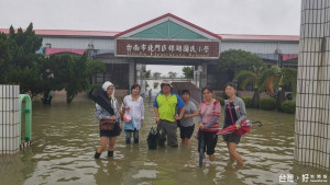 北門區錦湖國小教職員工涉水前進校園，在校園口的合照，幾乎沒有笑容。（記者邱仁武／攝）