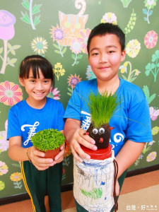 安定國小小朋友白晏甄、邱德合開心展示自己種植的火龍果苗、達冠草