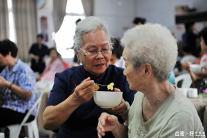 73歲的慈濟台南志工陳喜久（左）餵失能老人吃飯。