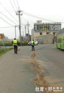 四湖所警員為避免影響用路人安全，立即以砂土覆蓋油漬，待吸附後清除，讓路面恢復清潔，路過民眾給予高度肯定。（記者陳昭宗拍攝）