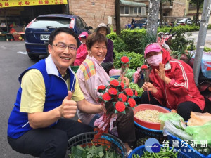 市議員楊朝偉十四日至市場和人多的地方發送有LED造型，兼具環保功能的康乃馨花，婆婆媽媽們反應熱烈。(記者陳寶印攝)