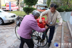 鎮公所員工協助老人家將物資綁在腳踏車上方便帶回家。