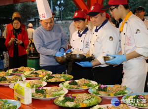 副市長侯友宜出席莊敬愛心圍爐，戴上廚師帽，扮演廚師撈取大紅蝦，還跟學生一起調配冷盤料並幫忙上菜。（圖／記者黃村杉攝）