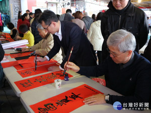 新春贈春聯活動中，蘆竹區長褚春來（右一）、立法委員鄭運鵬（中）現場揮毫，引起民眾爭相索取。