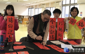 鶯歌分館舉辦「揮毫迎福旺旺來」活動，楊秋承館員寫春聯送給到館借書民眾。（圖／記者黃村杉攝）