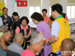 副局長呂春萍〈穿紫色衣〉與清海無上師代表發放紅包及物資給街友。（圖／記者黃村杉攝）