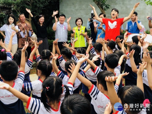 蔣絜安局長與幼兒園小朋友於伯公伯婆雕塑前一同吟唱客語童謠