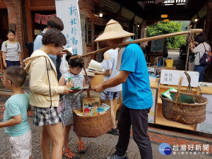 深坑分館主任楊俊生肩挑書香扁擔於老街上漂書，向遊客推薦好書閱讀，借書還可享有深坑美食的消費優惠。（圖／深坑分館提供）