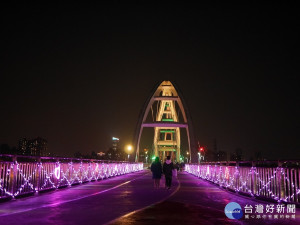 新月橋觀景休憩平台上周邊護欄以粉紫菱格圖案延伸至橋拱，其中點綴著溫暖的愛心燈片，以浪漫的氛圍迎接著前來新月橋的情人 。（圖／高管處提供）