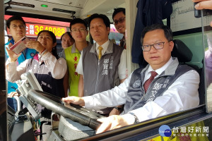 桃園市公車將全面加裝人車衝突預防設施，桃園市長鄭文燦坐上駕駛座親自查看公車A柱旁玻璃貼附凸透鏡。