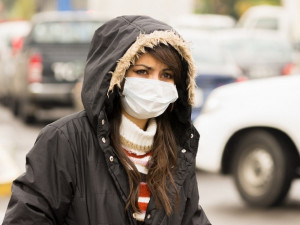 portrait of young girl walking wearing jacket and a mask in the city street concept of  pollution