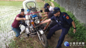 男子騎車跌入田埂，警民合作抬車助脫困。

