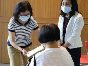 社會局副局長許秀能（左）代侯友宜市長致上10萬元慰問金給因染疫往生者家屬