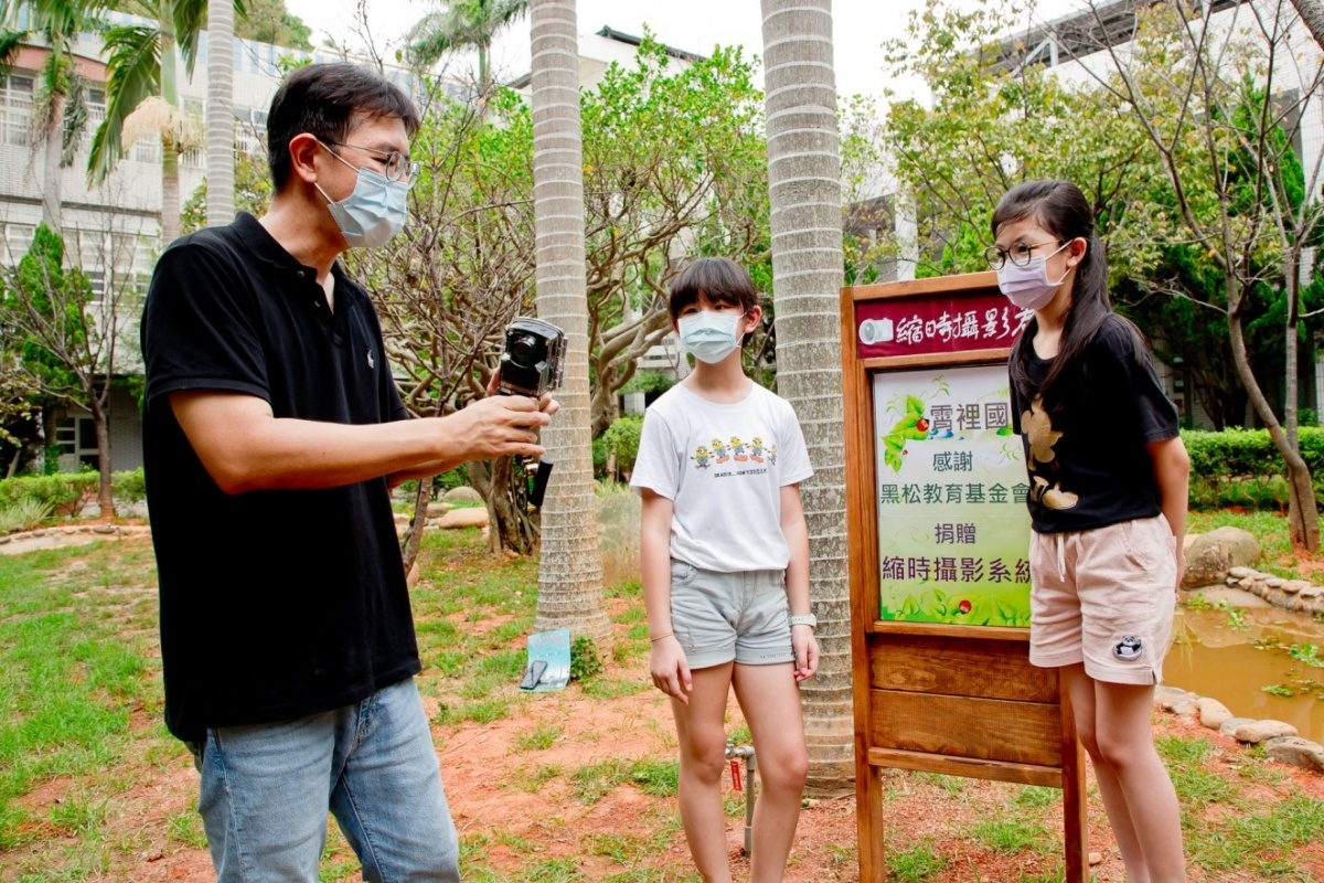 今日縮時攝影設備正式啟用，霄裡國小學務主任李士豪(左一)向學生講解如何利用縮時攝影機觀察生態。